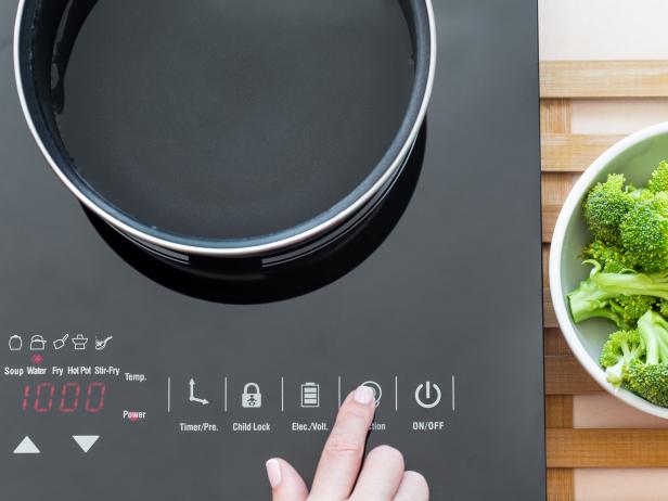 Woman select function on Induction stove, cooking broccoli process