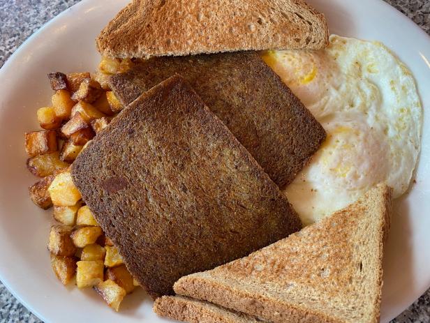 A breakfast consisting of fried eggs, scrapple (liver mush), potatoes, and toast.