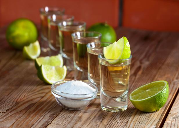 Small glasses of tequila and lime slices.