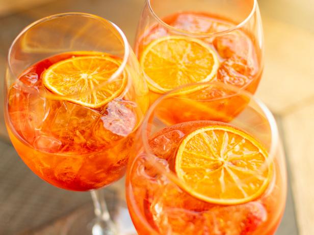 Italian aperitif aperol stpritz with ice and a slice of orange in large round glasses on a wooden table in a bar in Italy