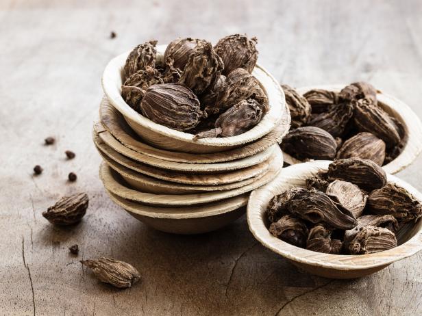 Black cardamom in bowls on wooden background indian spice close-up