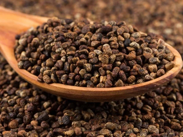 Decorticated cardamom seeds in a wooden spoon