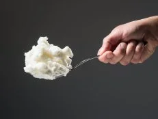 Man's hand holding a spoon full of vegetable shortening