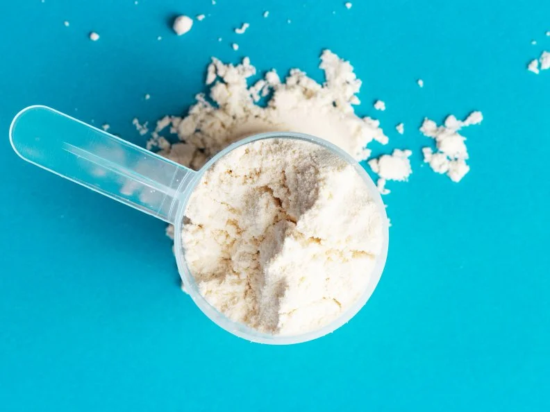 Scattered protein in scoop on a blue background close-up, top view