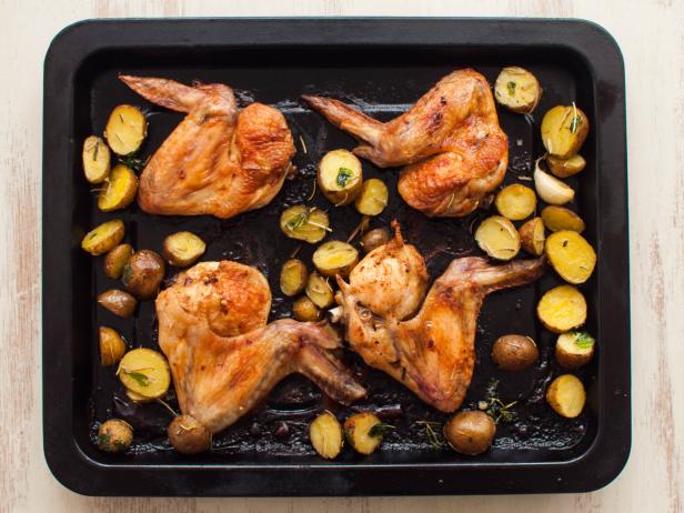 High angle view of freshly baked chicken wings with marble potatoes on a baking pan