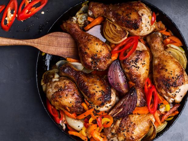 Spicy roasted chile miso  chicken drumsticks  with bell pepper and onion in cast iron skillet viewed from above
