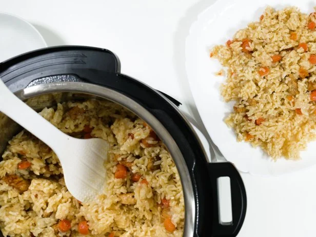 Risotto with pork and vegetables cooked in pressure cooker, close up on white background