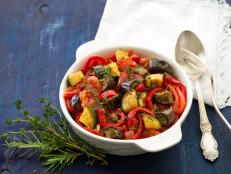 Ratatouille, a traditional French dish of fresh vegetables in a white ceramic bowl on a dark blue background