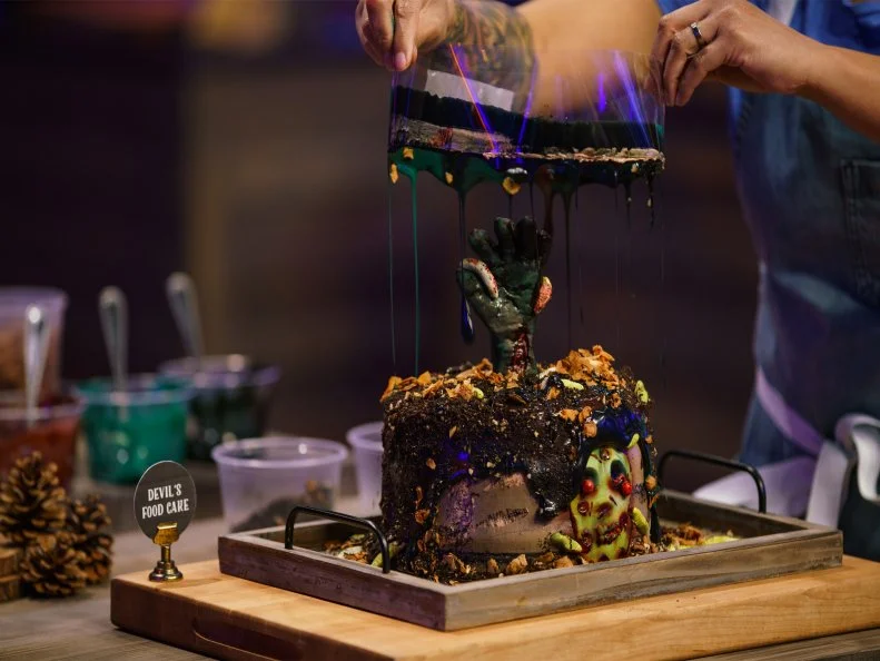 Ashley Wong's Zombie Face With Maggots Tsunami Devils Food Cake is made with toasted pecan coconut filling, chocolate buttercream with a white chocolate ganaache cascading icing and candied coconut skin flakes, as seen on Halloween Baking Championship, Season 7.