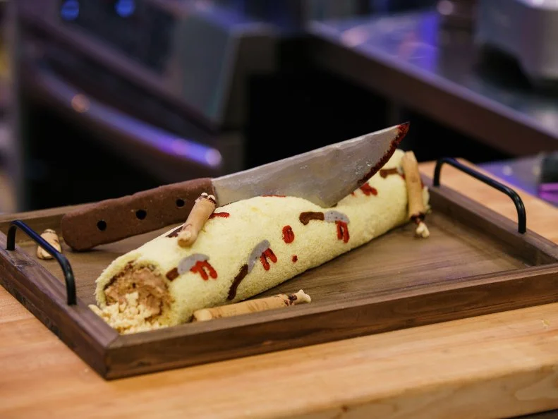 Contestant Adina Schaefer's Peek-A-Boo Roll Cake is a dark chocolate and passion fruit chocolate cake flavored with Chocolate Ganache, Passion Fruit Milk Crumble and Chocolate Mousse, as seen on Halloween Baking Championship, Season 7.