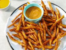 What's my secret for super-crispy sweet potato fries? I actually have two. First, I soak the potatoes in cold water to remove the excess starch. Then, I give them a toss in a cornstarch and seltzer water mixture. The cherry on top? I dust these with a spicy-sweet spice blend and serve them with two different awesome sauces. Bet you can't eat just one!