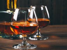 Glass of brandy or cognac with bottle on the wooden table.