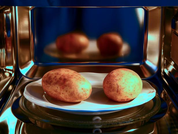 Two baked potatoes ready to cook in a microwave oven