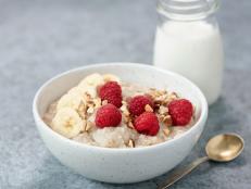 Bowl of oatmeal porridge with raspberries and banana slices. Milk oatmeal porridge in bowl
