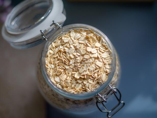 A shot of a glass jar that is filled with oats on a counter top in a kitchen.