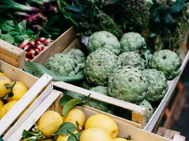 Boxes with various fresh fruits and vegetables standing on stall of nice food market