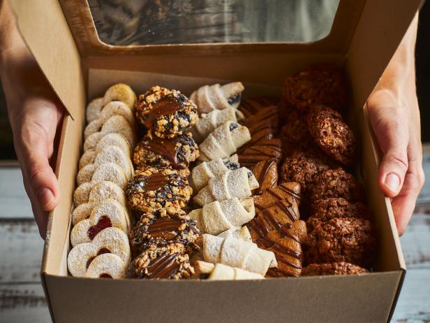 Woman holding cardboard take away box filled with Christmas pastry, close up