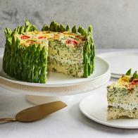 Description: Food Network Kitchen's 4-Cheese Garden Vegetable Frittata. Keywords: Cream Cheese, Goat Cheese, Chives, Parsley, Jumbo Asparagus, Heavy Cream, Parmesan, Mozzarella, Baby Spinach, Eggs, Scallions, Heirloom Grape Tomatoes.