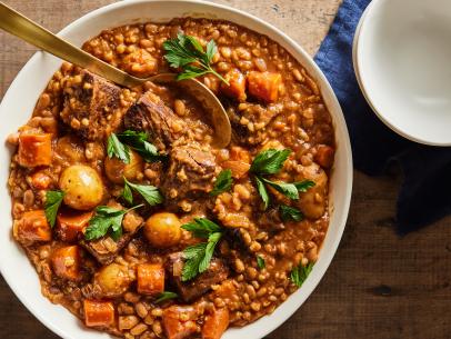 Description: Food Network Kitchen's Cholent. Keywords: Great Northern Beans, Beef Short Ribs, Red Wine, Yellow Onions, Creamer Potatoes, Carrots, Garlic, Pearled Barley, Tomato Paste, Honey.