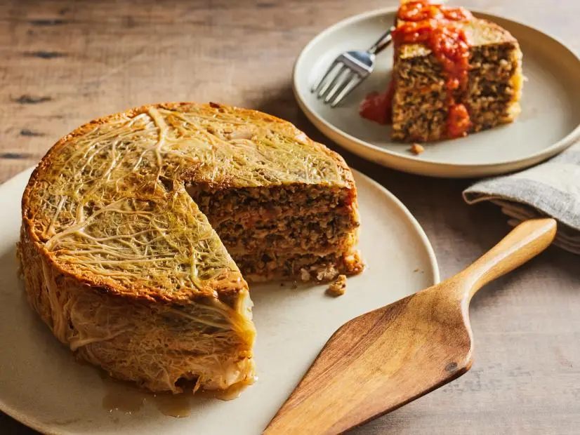 Description: Food Network Kitchen's Vegetarian Whole Stuffed Cabbage. Keywords: Savoy Cabbage, Garlic, Celery, Red Onion, Thyme, Paprika, Red Pepper, Cremini Mushrooms, Shiitake Mushrooms, Brown Rice, Parsley, Eggs, Marinara Sauce.
