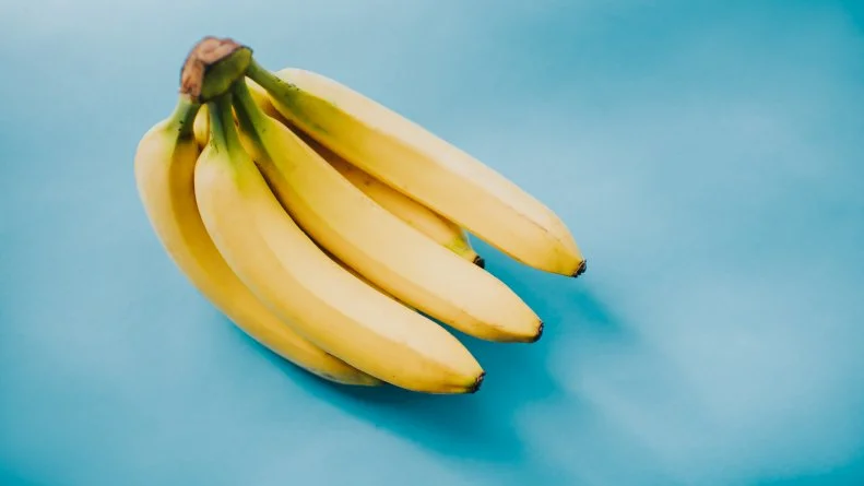 Bunch of Bananas on a blue backdrop. Space for copy.