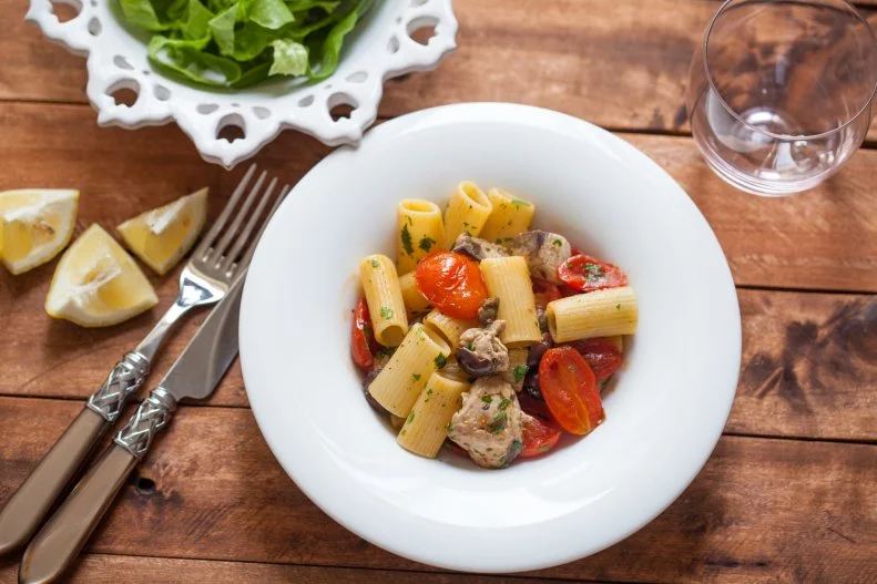 Rigatoni pasta cooked with tuna fish ,tomatoes and black olives, traditional italian cuisine. Home made tasty food.