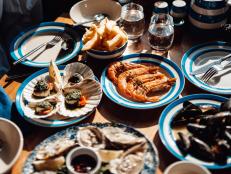 Various seafood with oysters, scallops, prawns and mussels freshly served on a wooden dining table with beautiful sunlight.
