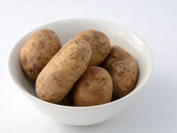 Raw uncooked potatoes in white bowl