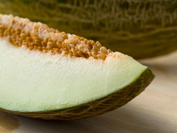 Piece of a juicy Piel de sapo melon with a blotched green peel close up