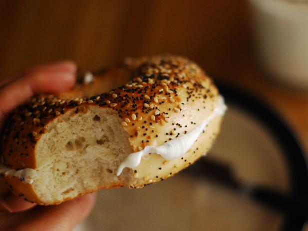 Bagel filled with cream cheese and milk for breakfast.