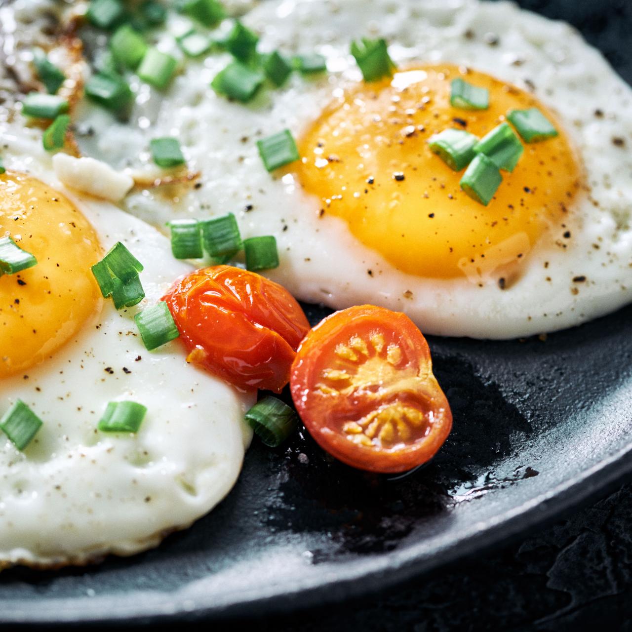 https://food.fnr.sndimg.com/content/dam/images/food/fullset/2022/01/03/sunny-side-up-egge-tomato-green-onion-black-plate.jpg.rend.hgtvcom.1280.1280.suffix/1641186588350.jpeg