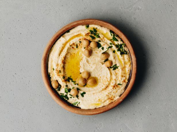 Hummus. Large bowl of homemade hummus garnished with chickpeas, red sweet pepper, parsley and olive oil, flat lay, middle east food