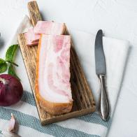 Bacon pancetta cut and sliced with herbs on white background with space for text.