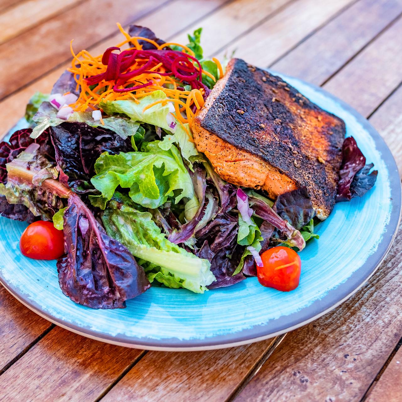 https://food.fnr.sndimg.com/content/dam/images/food/fullset/2022/01/14/blackened-salmon-baby-greens-tomato-carrot-beet-blue-plate-wood-surface.jpg.rend.hgtvcom.1280.1280.suffix/1642208350013.jpeg