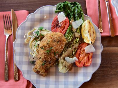 Close-up of Crispy Herb Crusted Chicken Cutlets, Grilled Tomato & Caesar Salad and Mushroom & Black Pepper Pasta, as seen on The Pioneer Woman, season 30.