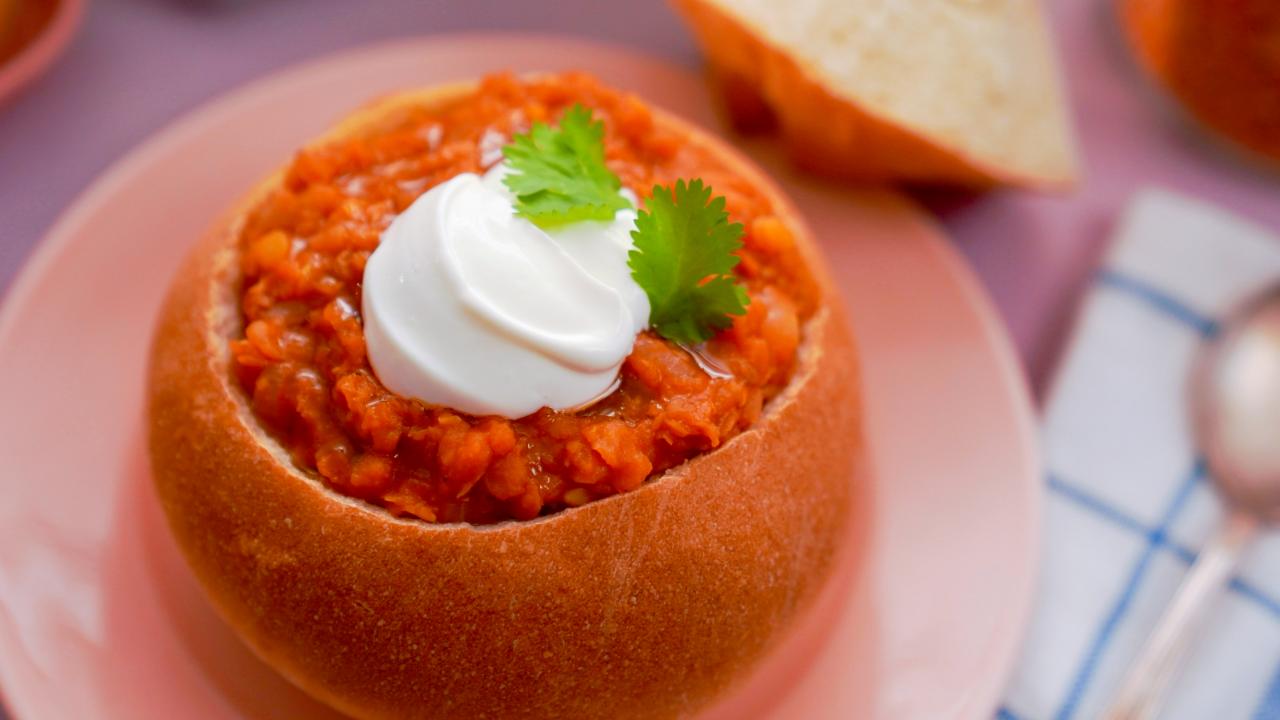 Fresh lentil soup in a white bowl, served in a restaurant setting