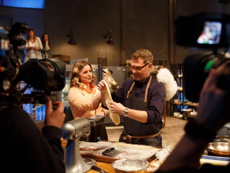Behind the scenes of co-host Damaris Phillips distracting chef Bobby Flay with cat puppets as he to prepare his Round 2 dish, as seen on Beat Bobby Flay, Season 24.