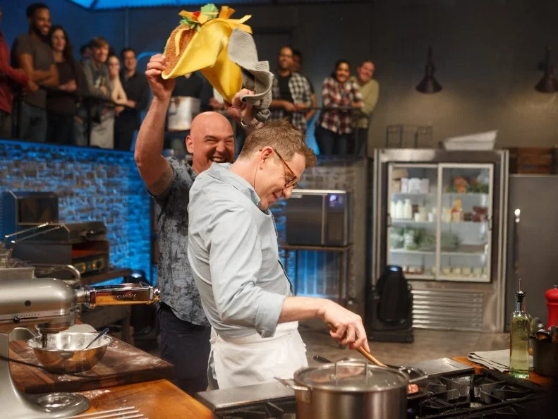 Co-Host Michael Symon tries to distract chef Bobby Flay mid-cook, as seen on Beat Bobby Flay, Season 20.