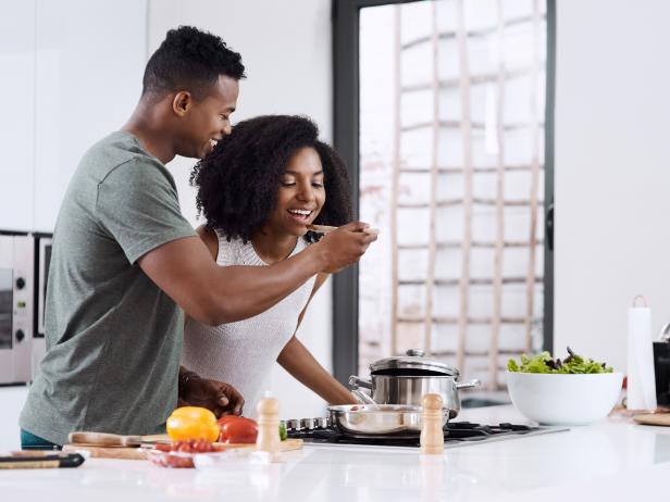 Cropped shot of a man having his wife taste the food that he's preparing