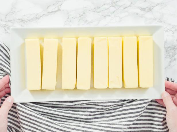 Step by step. Flat lay. Stick of butter at room temperature on a white plate.