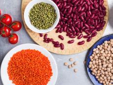 Selection of dry grains and beans, healthy food ingredients on gray background viewed from above