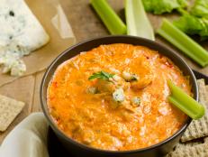 A bowl of Buffalo Chicken Wing Dip with blue cheese and celery in the background and crackers on the side.Similar Images: