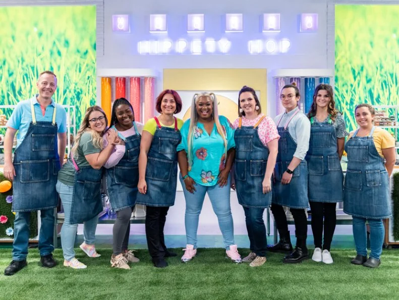 Portrait of host Sunny Anderson with contestants Sean Dwyer, Samantha Terrana, Sydney Perry, Tatiana Kovalenko, Whitney Ronzello, Brandon Ting, Kathleen Faliskie, and Brittany Lombardi, as seen on Spring Baking Championship: Easter Season 2.