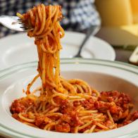 juicy spaghetti with tomato sauce in white plate in restaurant