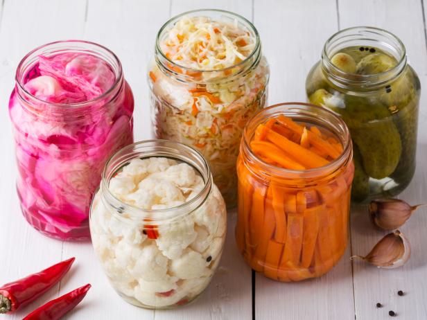 Fermented vegetables. Homemade marinated cabbage with carrot and cucumbers, sauerkraut sour in glass jars. Preserved canned vegetables, superfoods and vegetarian food.