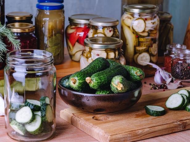 Kitchen pantry. Making fermented pickled cucumbers. Canning process, fresh vegetables, jars with preserved vegetarian food on wood rustic table. Zero waste food concept