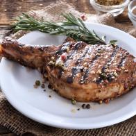 Juicy grilled pork chop with spices on a white plate