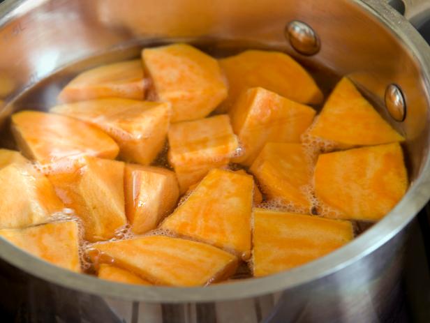 Chopped sweet potatoes coming to the boil in pan
