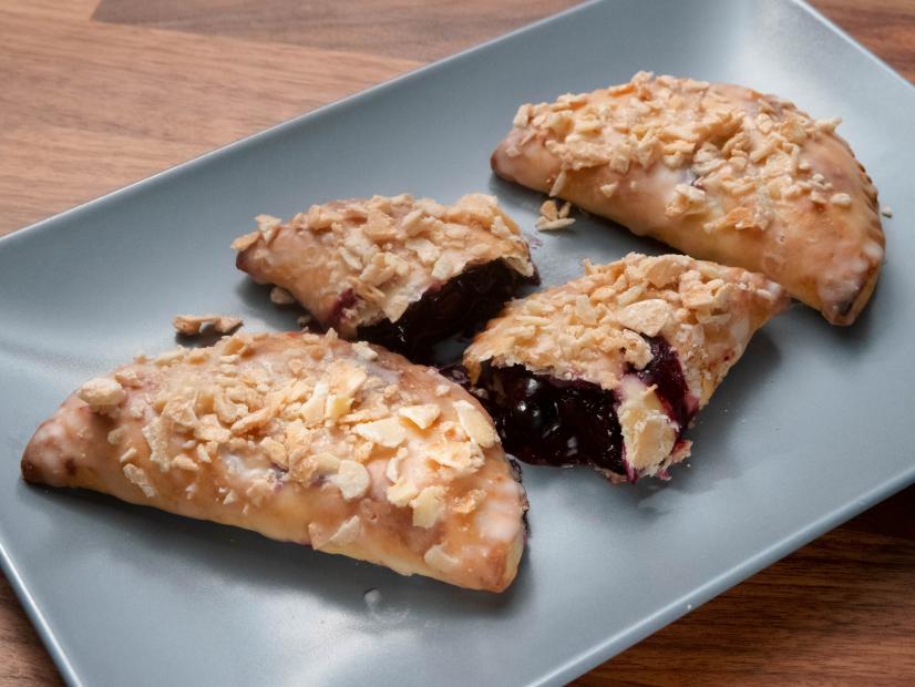 Anne Burrell’s Peach and Blueberry Hand Pies with Vanilla Glaze and Candied Almonds are displayed, as seen on Worst Cooks in America, Season 23.