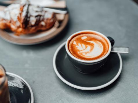 https://food.fnr.sndimg.com/content/dam/images/food/fullset/2022/03/30/latte-in-black-cup-with-coffee-shop-desserts.jpg.rend.hgtvcom.476.357.suffix/1648675207115.jpeg